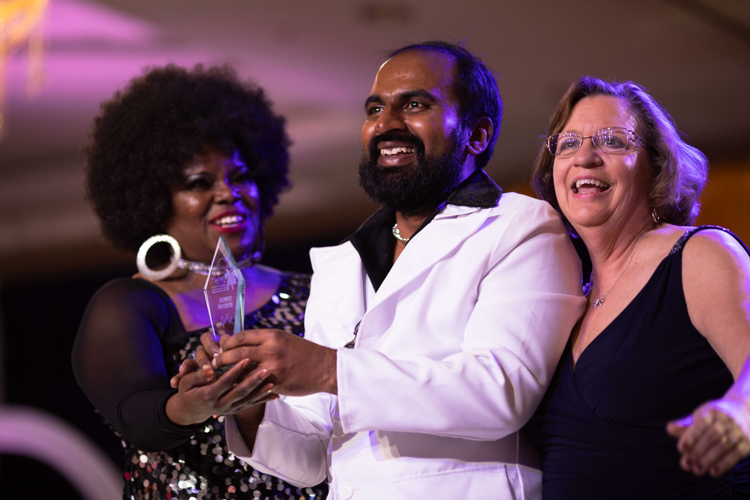 Image of three people smiling after one person won a trophy at Dancing with the St. Louis Stars 2024